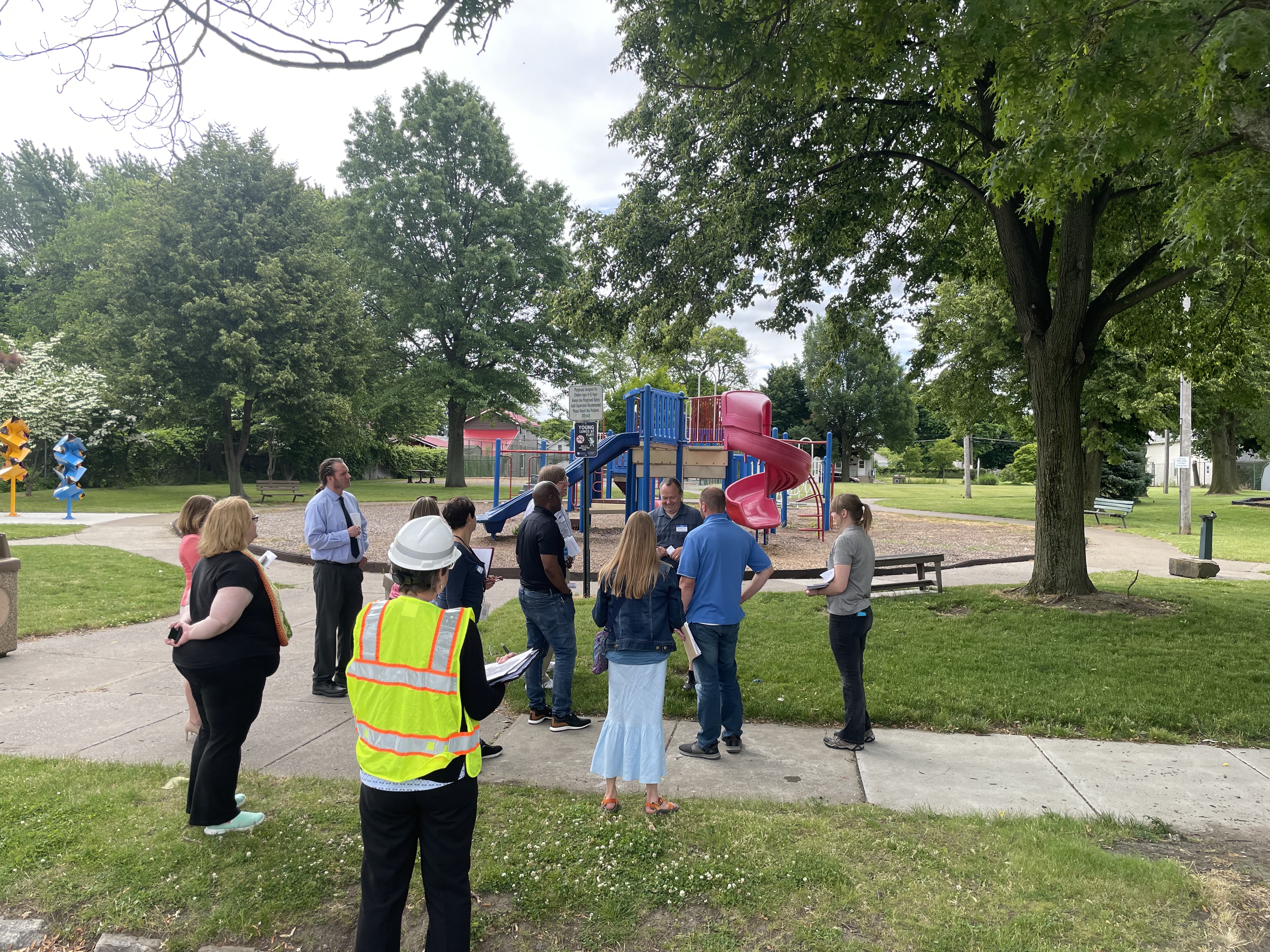 group of people standing park in front of playground equipment