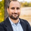 Man with facial hair standing outside smiling