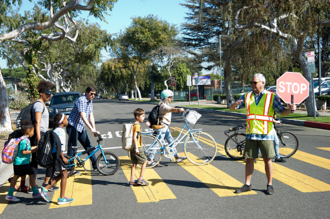 children walking in crosswalk with crossing guard