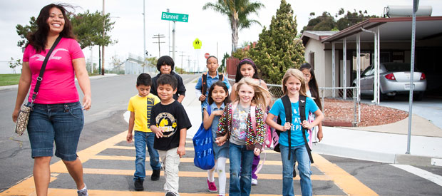 children walking in crosswalk with crossing guard